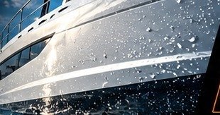 White boat bow with marine paint protection film cutting through water spray